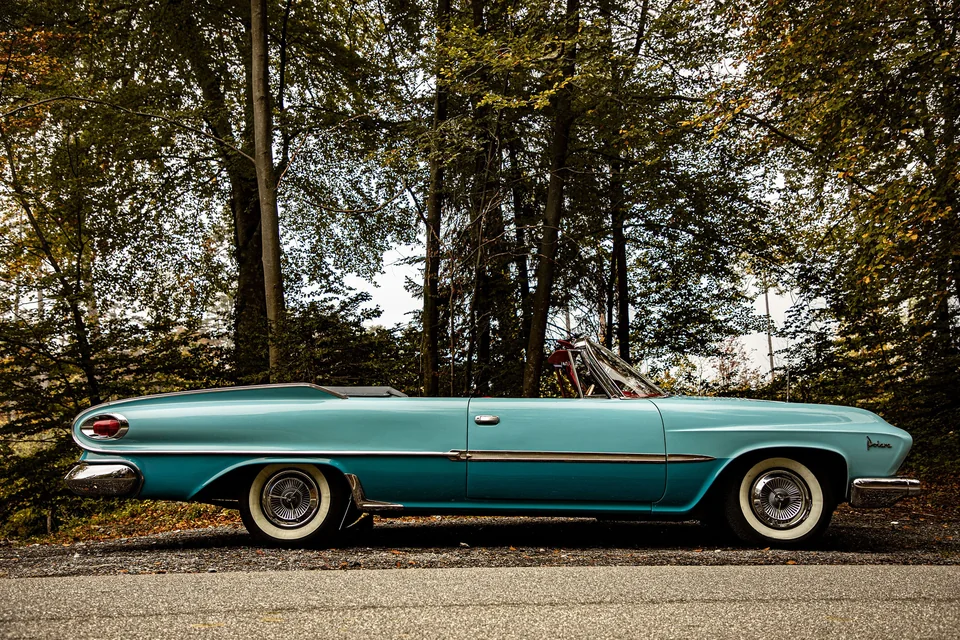 Volledig zijaanzicht van de turquoise Dodge Polara met open kap en witte banden