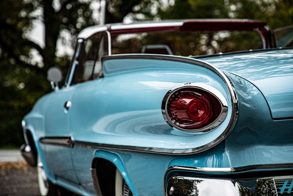 Close-up van de iconische vleugelachtige achterkant en het opvallende ronde achterlicht van een lichtblauwe klassieke Dodge Polara.