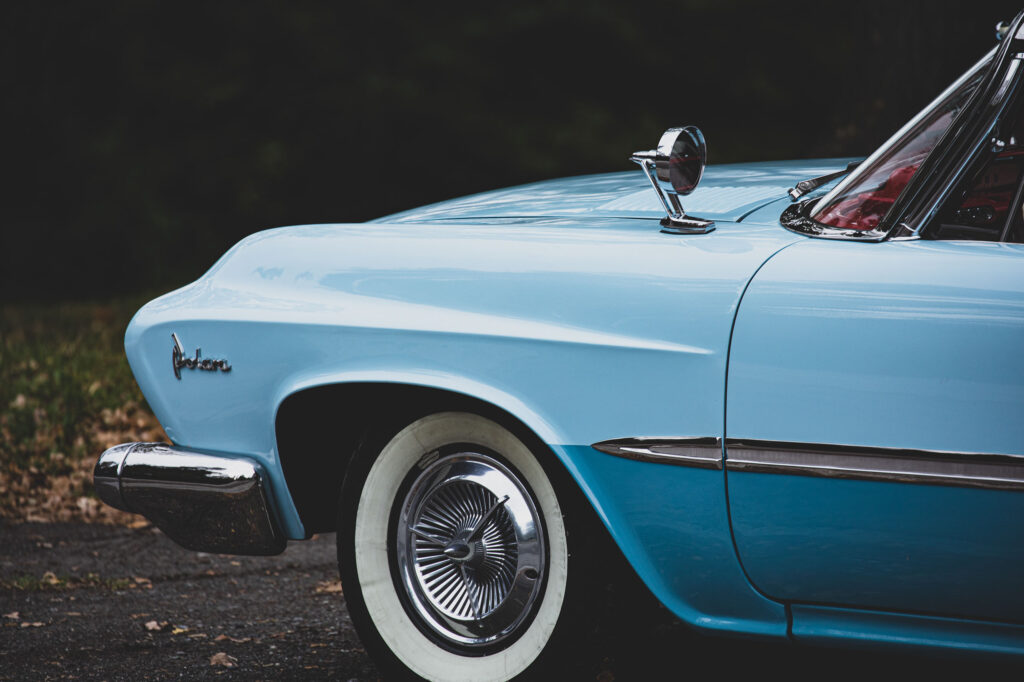 Zijaanzicht van de voorkant van een lichtblauwe klassieke Dodge Polara met chromen details, whitewall banden en een zijspiegel.